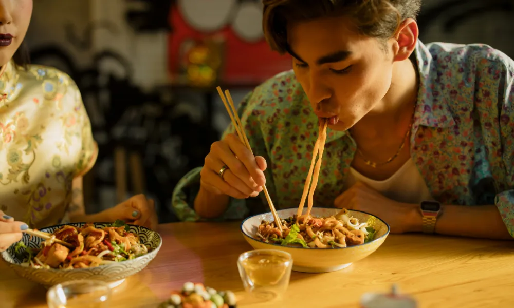 a man eating food with chopsticks after 7 pm